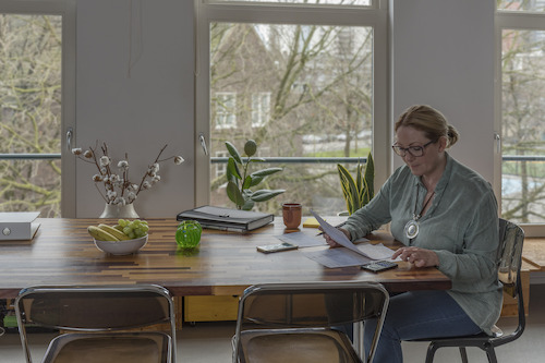 Vrouw aan tafel met papieren en rekenmachine 